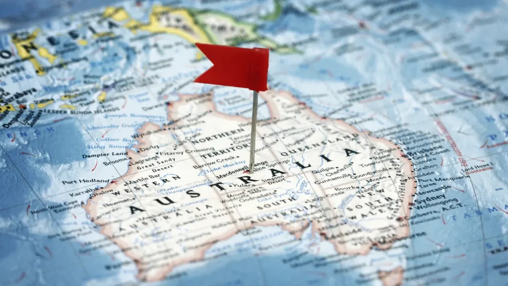 Mapa da Austrália com um alfinete de bandeira vermelha marcando o país. Saiba qual é a melhor época para viajar para a Austrália e planeje sua viagem com antecedência.
