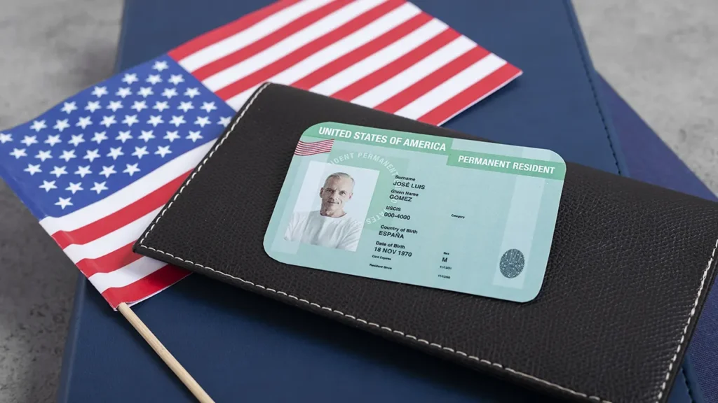 Imagem de um cartão de residência permanente dos Estados Unidos sobre uma bandeira americana. Excelente para entender os tipos de visto americano.